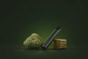 Eine THCa-Blüte, eine Vape und ein Stück Hasch nebeneinander auf dunklem Grund